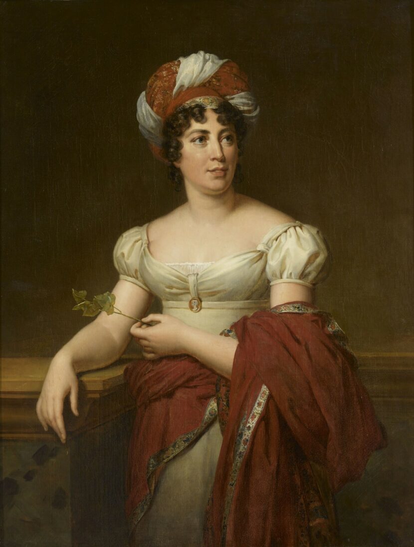 An oil portait of Germaine de Staël wearing a red and white turban and holding a sprig.