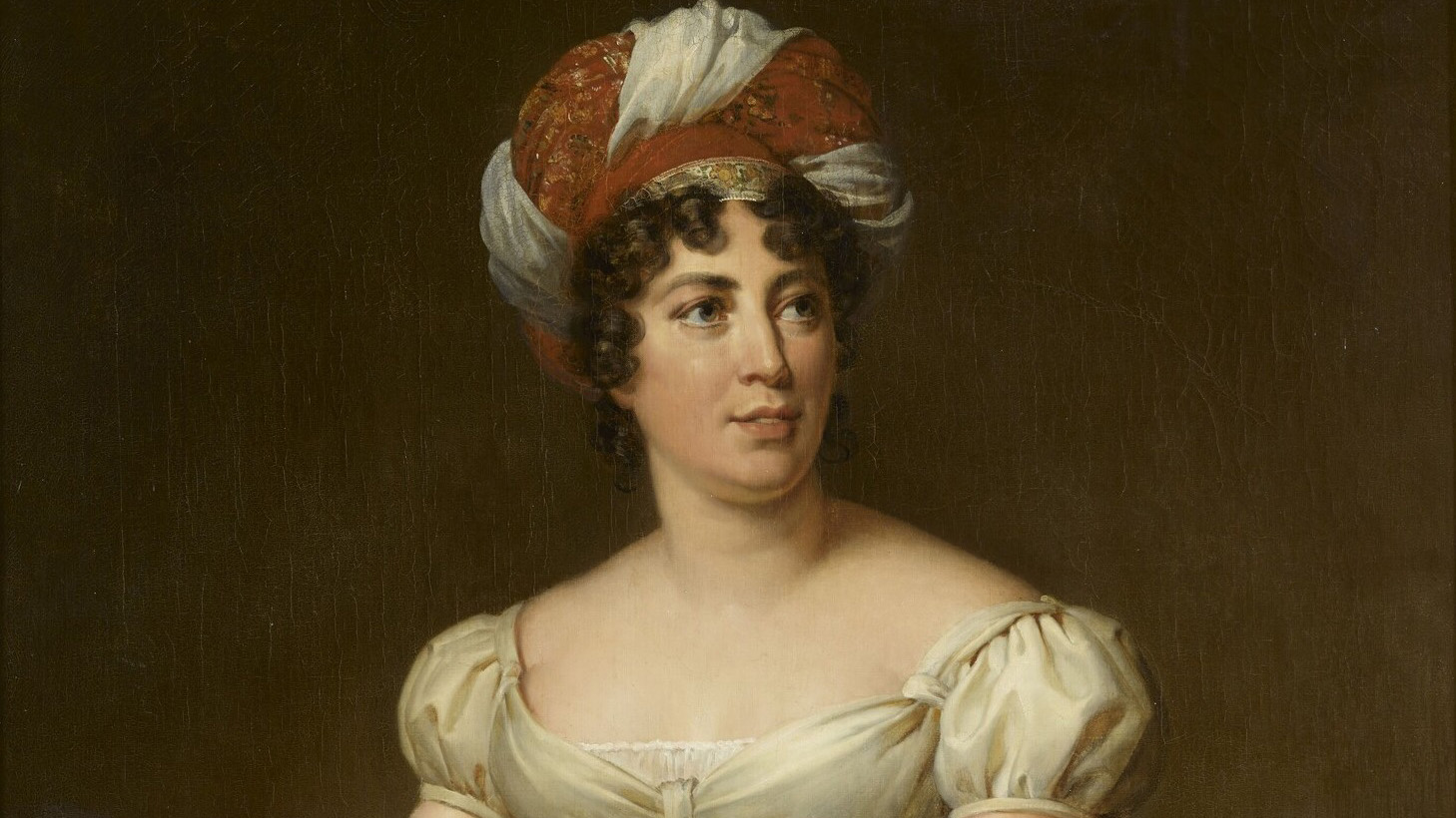 A detail of an oil portait of Germaine de Staël wearing a red and white turban.