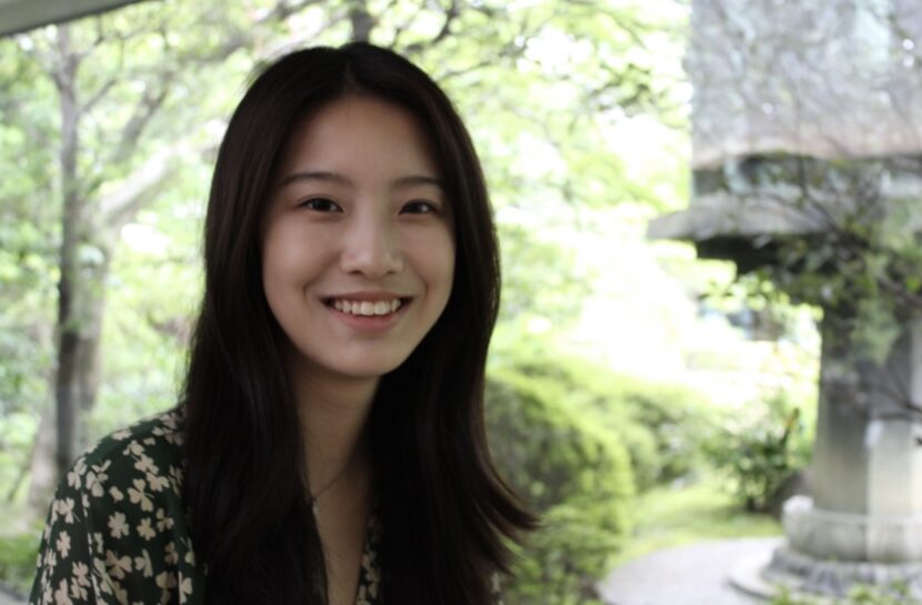 Photo of Joyce Li smiling at the camera with a blurred background of greenery